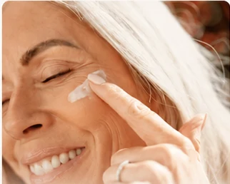 Skincare — a woman applying cream to her cheek
